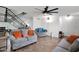 Modern living room with tile floors, ceiling fan, updated staircase, and comfortable gray sofas with bright accent pillows at 2912 E Clarendon Ave, Phoenix, AZ 85016