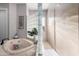 Bathroom featuring a soaking tub with marble surround and glass block partition at 2939 E Huber St, Mesa, AZ 85213