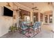 Cozy covered patio with outdoor dining set, ceiling fan, and TV for relaxing entertainment at 2939 E Huber St, Mesa, AZ 85213