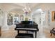 Elegant piano room featuring a grand piano, chandelier, and built-in shelving at 3447 E Kenwood St, Mesa, AZ 85213