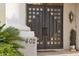 Close-up of the elegant front door with decorative windows, set against a stucco facade and lush greenery at 402 E Windmere Dr, Phoenix, AZ 85048