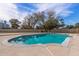 Sparkling turquoise swimming pool surrounded by a patio and mature trees at 4542 W Villa Theresa Dr, Glendale, AZ 85308