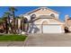 Tan two-story house with white garage doors and palm trees at 6970 W Morning Dove Dr, Glendale, AZ 85308