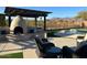 Covered patio area with a fireplace, outdoor seating, and backyard views with mature landscaping at 9900 E Desert Trail Ln, Gold Canyon, AZ 85118