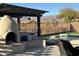 Covered patio area with a fireplace overlooking the pool and backyard with mountain views at 9900 E Desert Trail Ln, Gold Canyon, AZ 85118