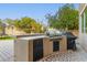 Outdoor kitchen with built-in grill and mini-fridge, located in a backyard with mature trees at 1078 W Spur Ct, Gilbert, AZ 85233