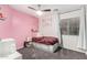 Bright bedroom with pink walls, a ceiling fan, window and a bed with built-in storage drawers at 15348 W Banff Ln, Surprise, AZ 85379