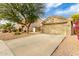 Tan house with a two-car garage and landscaping at 15348 W Banff Ln, Surprise, AZ 85379