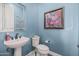 Powder room with pedestal sink, toilet and decorative accents at 18111 W Desert Sage Dr, Goodyear, AZ 85338