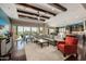 Spacious living area with wood beams, a fireplace and view of pool at 18111 W Desert Sage Dr, Goodyear, AZ 85338