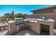 Modern outdoor kitchen with grill, sink, and bar seating at 18111 W Desert Sage Dr, Goodyear, AZ 85338