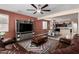 Open concept living room features a large leather sofa, stylish ceiling fan, and entertainment center at 2036 E Stacey Rd, Gilbert, AZ 85298