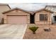 Tan house with a pink garage door and desert landscaping at 45331 W Applegate Rd, Maricopa, AZ 85139