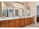 Bathroom with double sinks, wood cabinets, and a large mirror at 10921 W Bermuda Dr, Avondale, AZ 85392