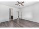 Bedroom with wood-look floors, ceiling fan, and access to bathroom at 12021 W Locust Ln, Avondale, AZ 85323