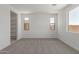 An airy bedroom showcases neutral carpet, three windows and a shelving unit at 18225 W Hess St, Goodyear, AZ 85338