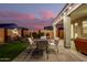 Evening view of backyard patio with seating area, fire pit, and string lights at 18258 W Spencer Dr, Surprise, AZ 85374