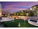 Evening view of backyard putting green, patio, and water feature at 19027 N 269Th Dr, Buckeye, AZ 85396