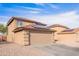 Two-story tan home featuring a tile roof and a two-car garage with solar panels set against a blue sky at 222 S 223Rd Dr, Buckeye, AZ 85326