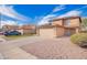 Two-story tan home featuring a two-car garage and a driveway with solar panels on the roof set against a blue sky at 222 S 223Rd Dr, Buckeye, AZ 85326