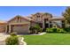 Two-story house with tan exterior, landscaping, and a large green lawn at 302 S Laguna Dr, Gilbert, AZ 85233