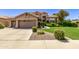 Tan two-story house with a lush green lawn and mature shrubs at 302 S Laguna Dr, Gilbert, AZ 85233