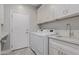 Bright laundry room with white cabinets, washer, dryer, and utility sink at 302 S Laguna Dr, Gilbert, AZ 85233