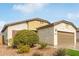 House exterior featuring a two-car garage and mature shrubbery at 5590 W Victory Way, Florence, AZ 85132