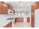 Kitchen with wood cabinets, white appliances, and a view of the living room at 5590 W Victory Way, Florence, AZ 85132