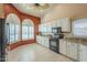 Well-lit kitchen with white cabinetry, granite countertops, black appliances, and arched windows at 9288 E Camino Del Santo --, Scottsdale, AZ 85260