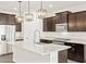 Island kitchen with dark cabinets, granite countertops, stainless steel appliances and pendant lights at 17457 W Eva St, Waddell, AZ 85355
