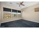 Well-lit bedroom with three windows, ceiling fan, and dark carpet at 30401 N 115Th Dr, Peoria, AZ 85383