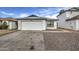 Front view of a single-story house with a white garage door and rock landscaping at 8728 W Vale Dr, Phoenix, AZ 85037