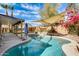 Backyard oasis featuring a sparkling pool, covered patio, and lush landscaping for outdoor enjoyment at 8818 W Virginia Ave, Phoenix, AZ 85037