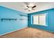 Spacious blue bedroom with bright walls, carpeted flooring, a window and floating shelves at 8818 W Virginia Ave, Phoenix, AZ 85037