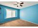 Bright blue bedroom featuring carpeted flooring, a window and electrical outlets at 8818 W Virginia Ave, Phoenix, AZ 85037