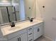 Modern bathroom with dual sinks, white cabinets with black hardware, and a glass-enclosed shower at 20596 N 226Th Dr, Surprise, AZ 85387