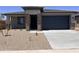 Charming single-story home with a desert landscape, brick accents, a dark garage door, and a covered porch at 20596 N 226Th Dr, Surprise, AZ 85387