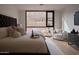Inviting bedroom with plush bedding, accent chair, and scenic views from the large window at 5000 N Camelback Ridge Rd # 109, Scottsdale, AZ 85251