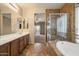 Bathroom with a glass enclosed shower, a soaking tub and a large vanity with double sinks at 9911 W Jessie Ln, Peoria, AZ 85383