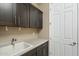 Functional utility room features dark cabinets and a sink, adjacent to a white paneled door at 12528 W Tuckey W Ln, Glendale, AZ 85307