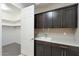 Functional utility room with dark cabinets, a sink, and access to a walk-in closet for extra storage at 12528 W Tuckey W Ln, Glendale, AZ 85307