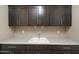 This utility room features ample dark wood cabinetry and a utility sink at 12528 W Tuckey W Ln, Glendale, AZ 85307