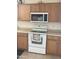 Traditional-style kitchen with wooden cabinets, white oven, microwave, and neutral countertops at 24246 W Tonto St, Buckeye, AZ 85326