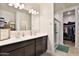 Bathroom featuring double sinks, modern vanity, and a glass-enclosed shower near a walk-in closet at 30968 W Monterey Ave, Buckeye, AZ 85396