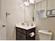 Cozy bathroom featuring a toilet, dark vanity with white countertop, framed mirror, and a patterned wall at 30968 W Monterey Ave, Buckeye, AZ 85396