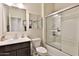 Bright bathroom featuring a vanity with modern fixtures, a toilet, and a glass-enclosed shower with white tile at 30968 W Monterey Ave, Buckeye, AZ 85396