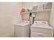 Laundry room with white washer and dryer, a shelf with laundry supplies, and overhead storage baskets at 30968 W Monterey Ave, Buckeye, AZ 85396