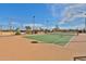 Well-maintained tennis court with green surface, surrounded by fencing and desert landscape at 30968 W Monterey Ave, Buckeye, AZ 85396