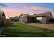 Dark-colored house with green lawn and sunset at 5013 W Orchid Ln, Glendale, AZ 85302